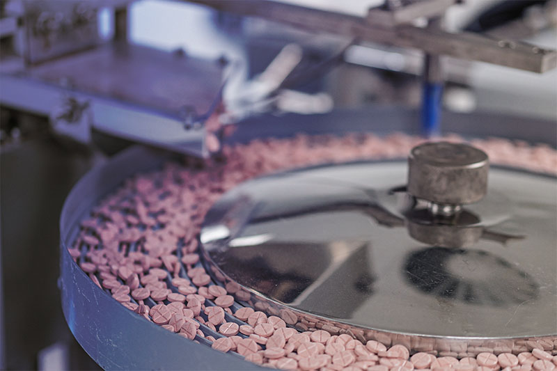 Macro shot of pills and capsules during production and packing process of modern supplement manufacturing factory. Tablet and Capsule manufacturing process.