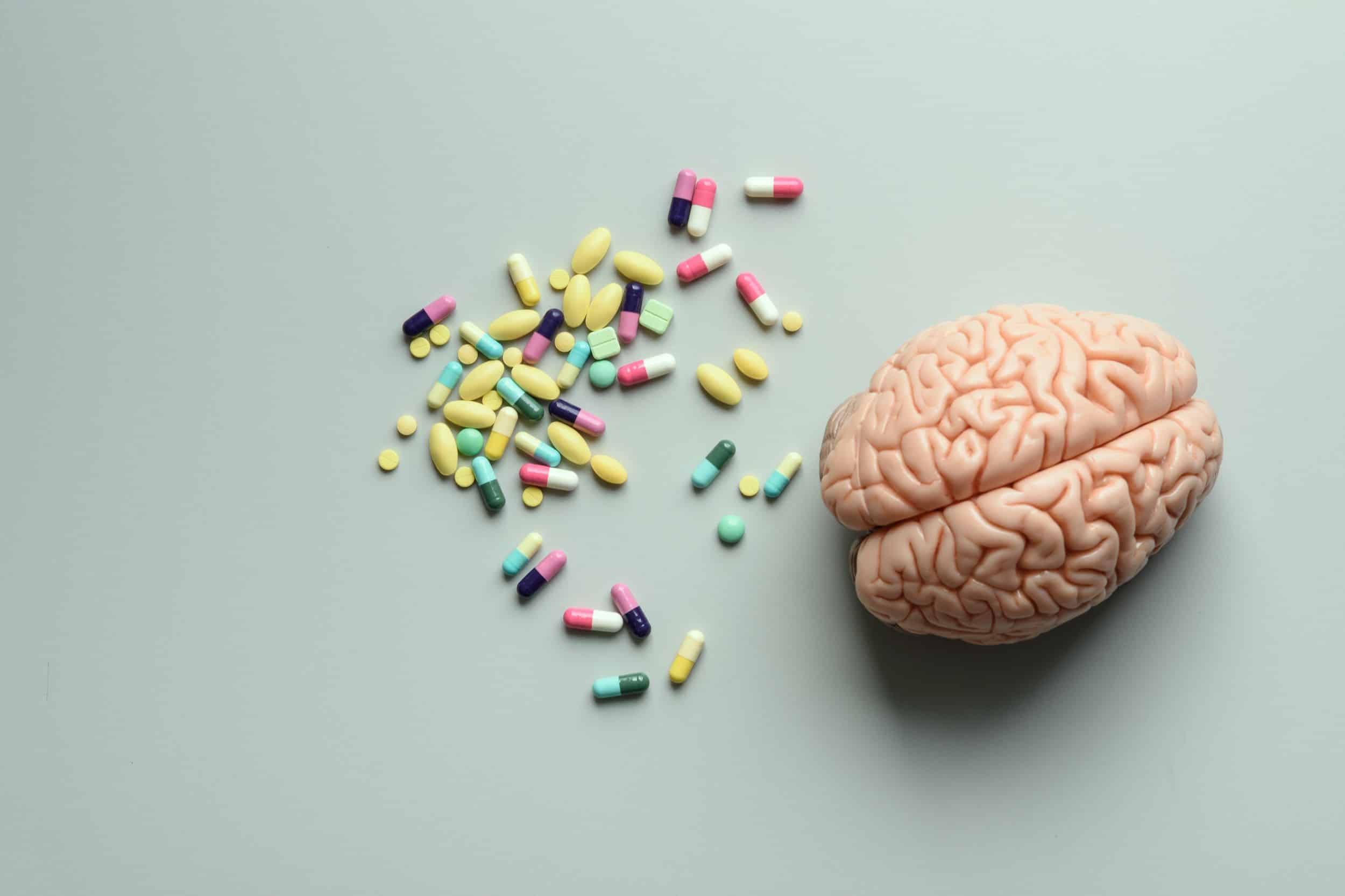 A model of a brain sitting next to a collection of nootropic capsules.